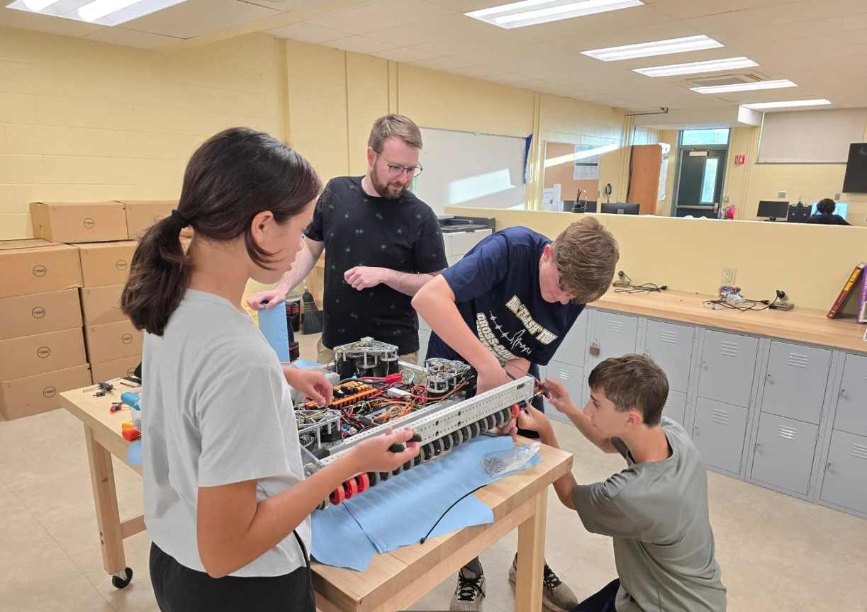 Students working together at organized tables in a simple robotics workspace